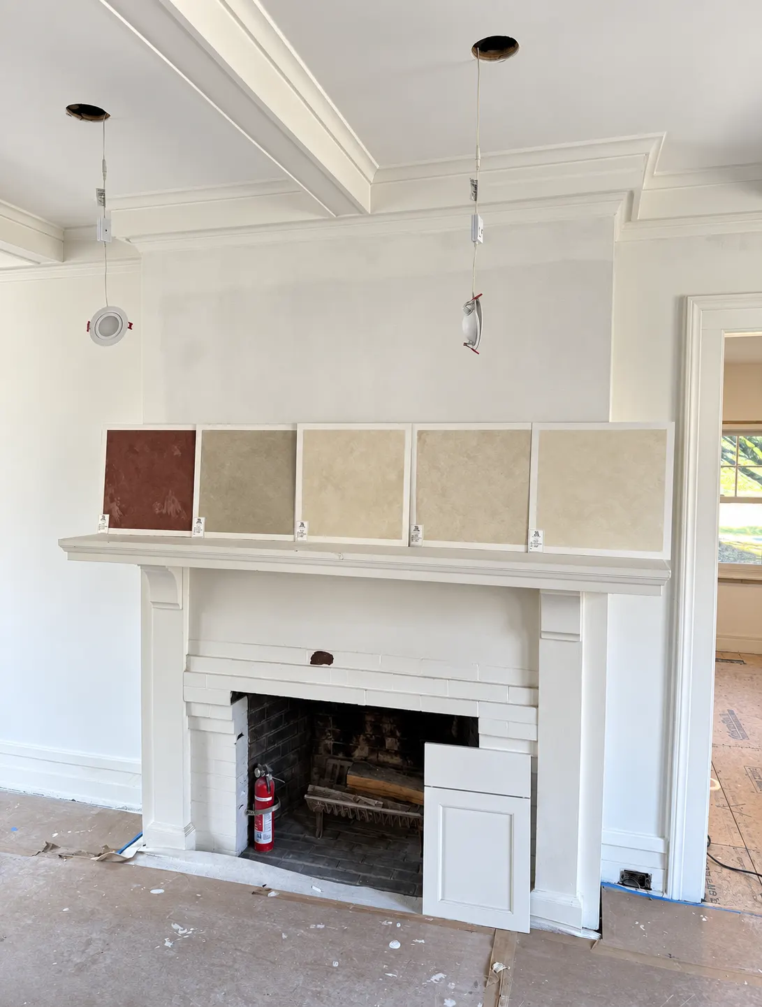 Limewash color consultation in a North Jersey home with five hand-finished sample boards, from terracotta to warm cream, displayed on a fireplace mantel