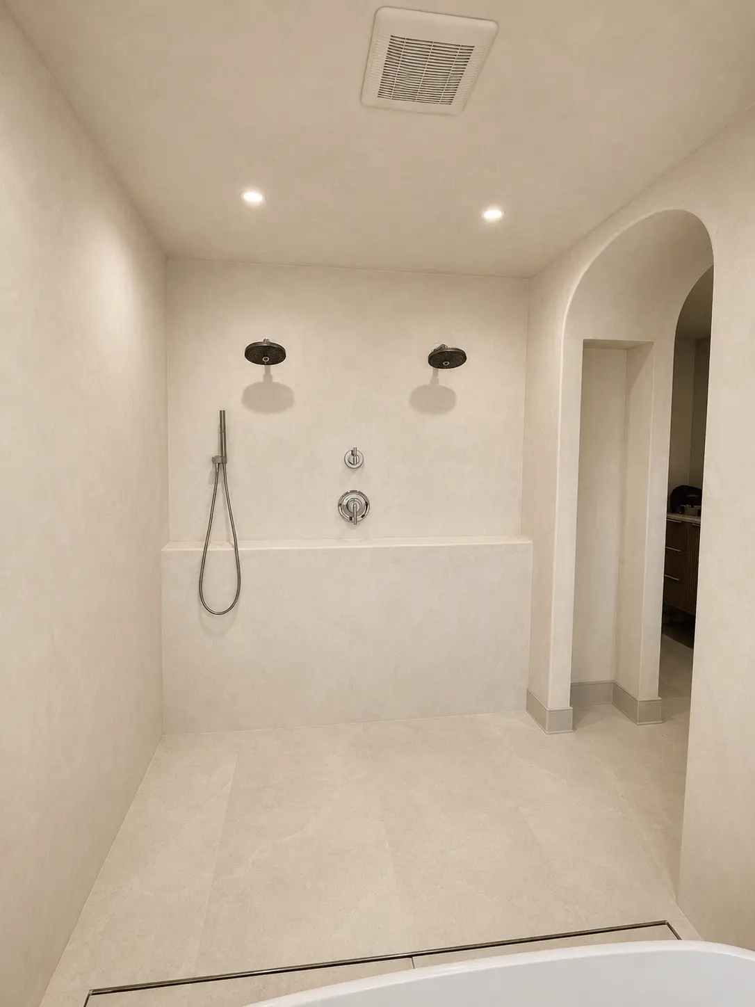 Seamless microcement wet room with arched opening and dual rain heads in Wayne, NJ