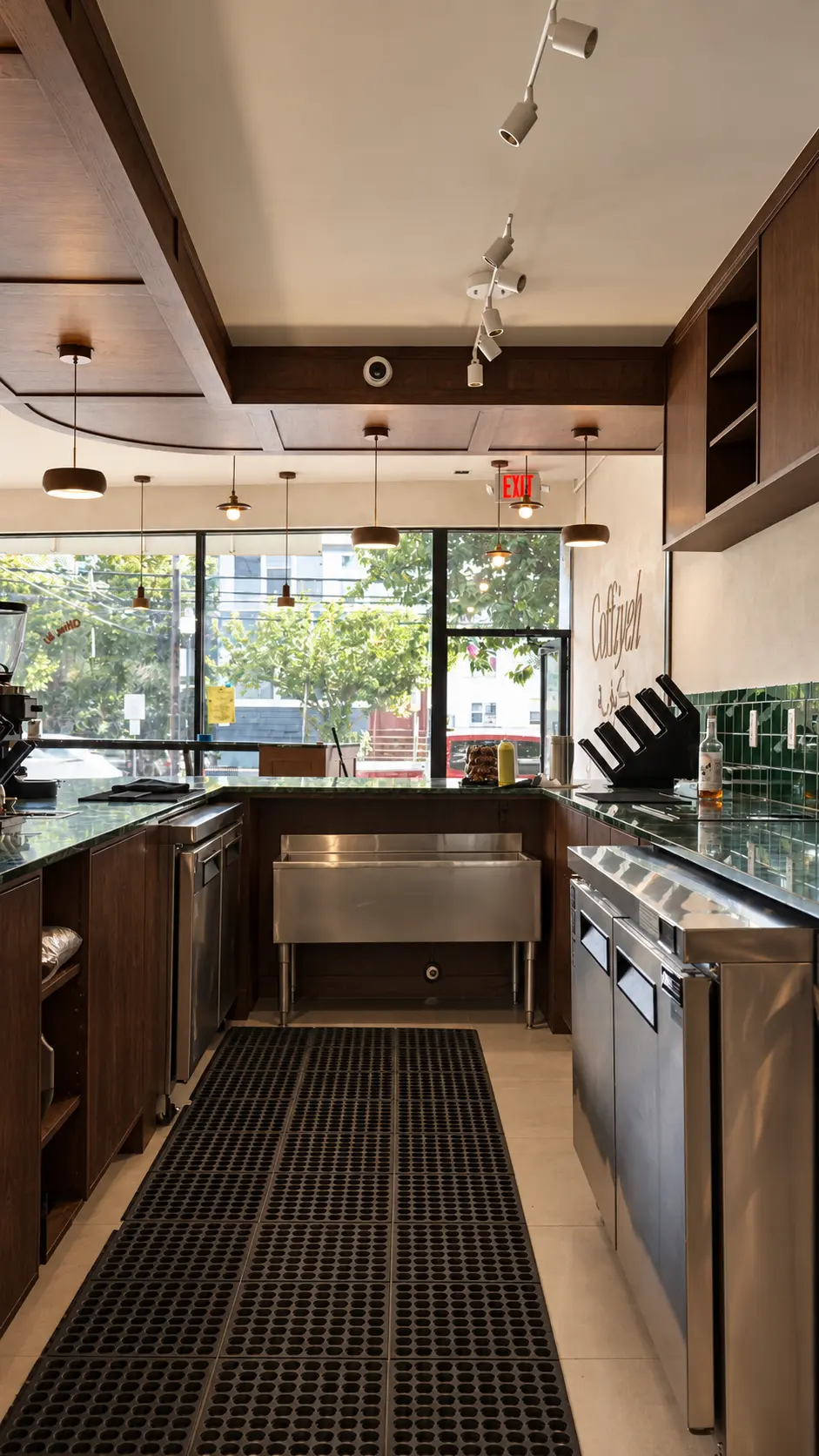 Barista station with stained wood cabinets, wood ceiling soffit and limewash logo wall at Coffiyeh coffee shop in Clifton, NJ