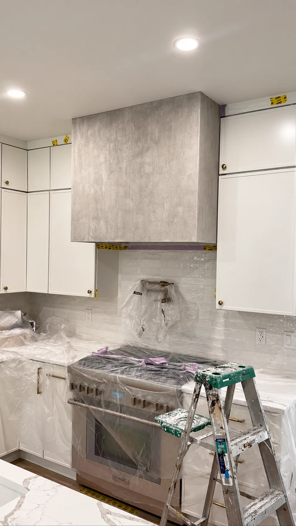 Textured plaster hood during installation with a ladder and protected kitchen counters — Ridgewood, NJ