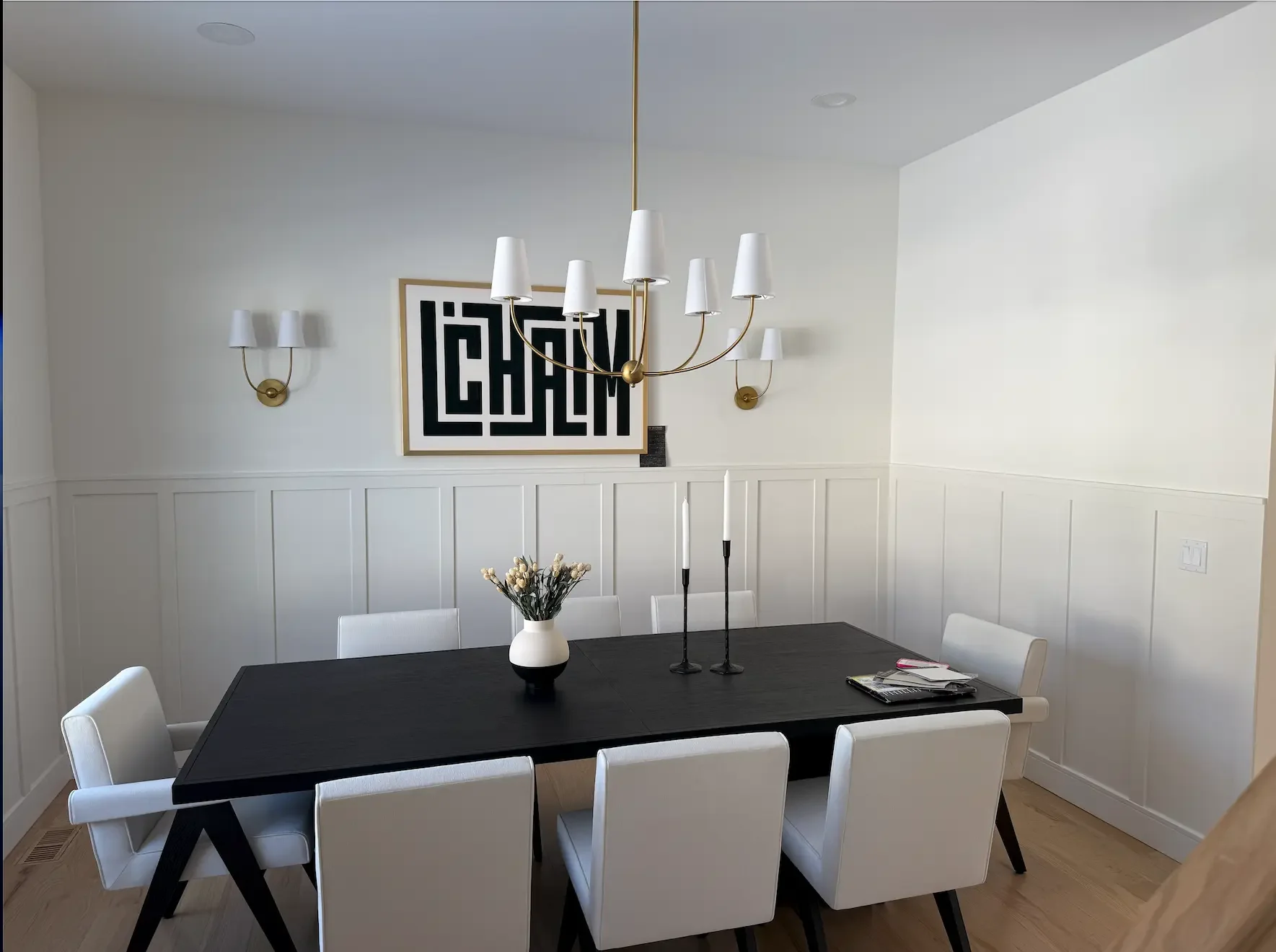 Finished warm white limewash dining room with brass chandelier, sconces and white wainscoting in Glen Rock NJ