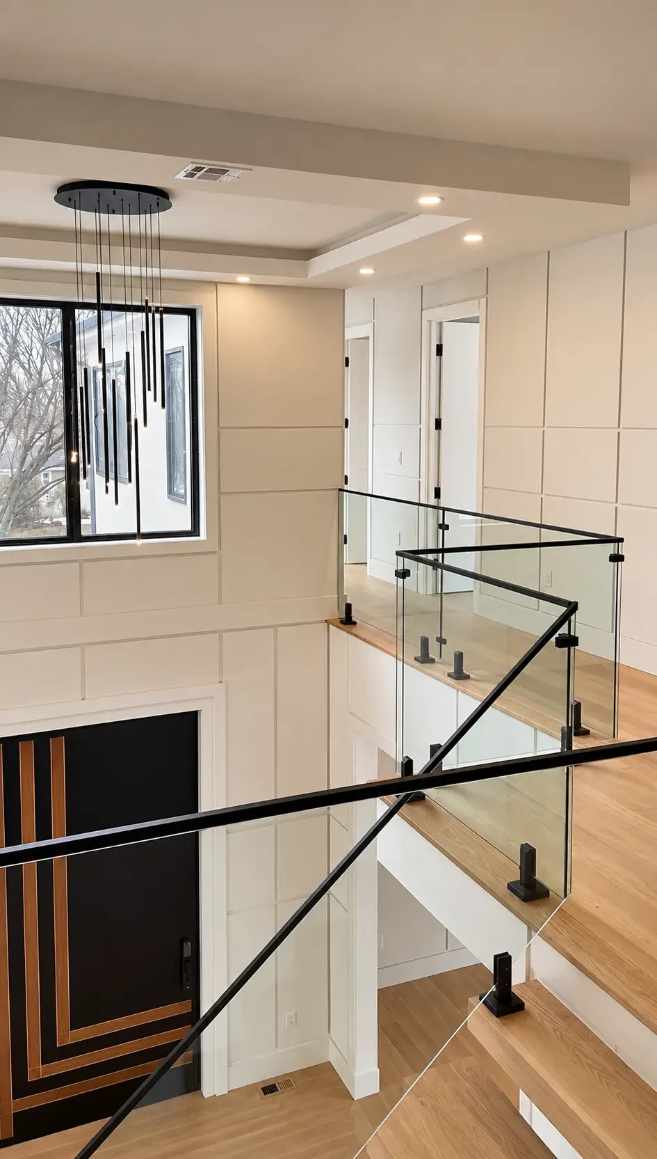 Two-story staircase with painted wall paneling and glass railing in Paramus, NJ