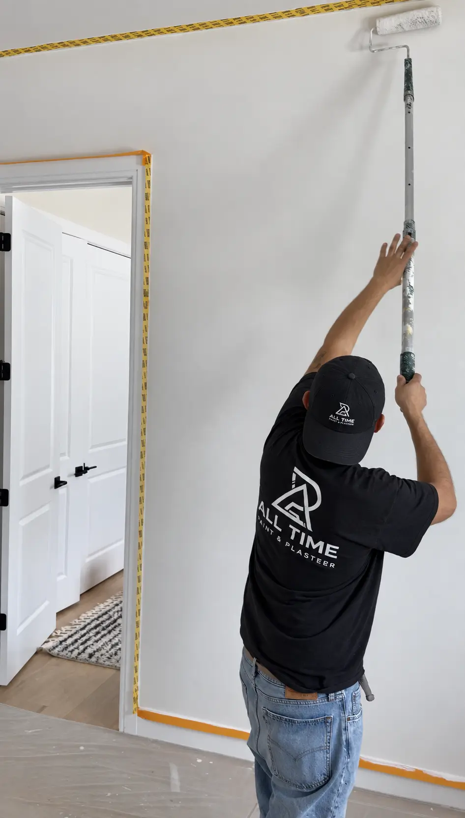 Painter applying a base coat to an interior wall as part of the professional limewash preparation process.