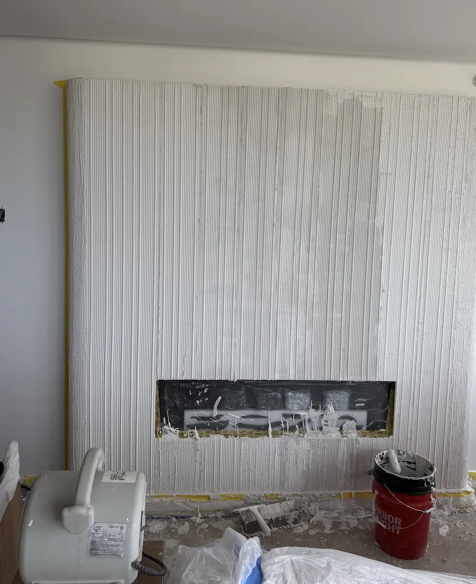 Fluted plaster fireplace wall in progress in New Brunswick, NJ, showing vertical reeds forming around the linear firebox