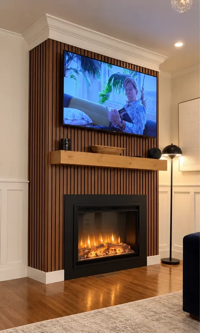 Builder-grade fireplace with wood slat wall before its plaster transformation in Cedar Grove, NJ