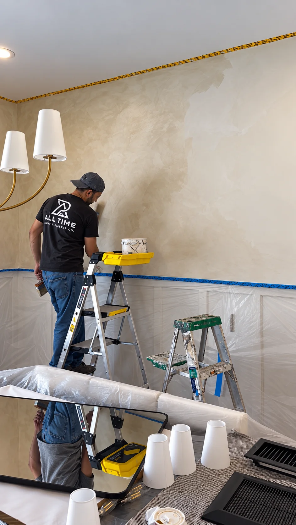 Painter applying warm white limewash to an upper dining room wall with a block brush in Glen Rock NJ