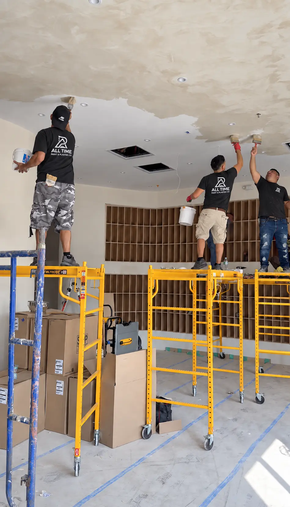 All Time Paint & Plaster crew hand applying limewash to a large interior ceiling from rolling scaffolds