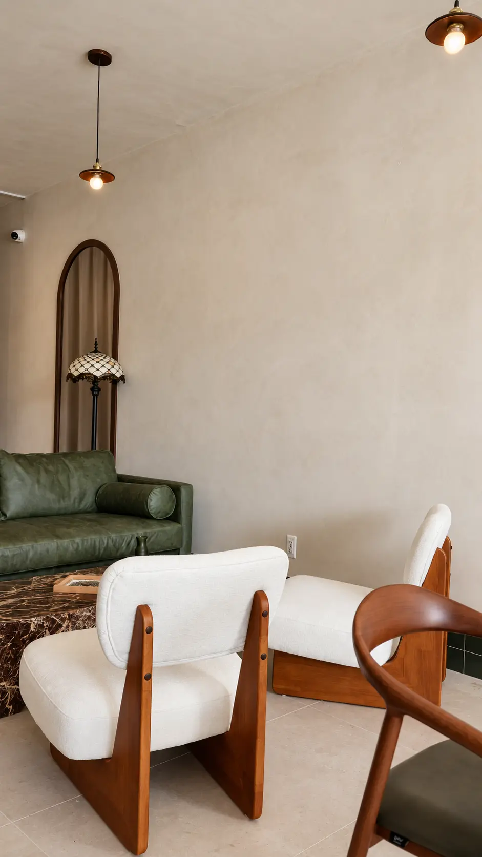 Limewash lounge corner with arched mirror, green sofa and boucle chairs at Coffiyeh, Clifton, NJ