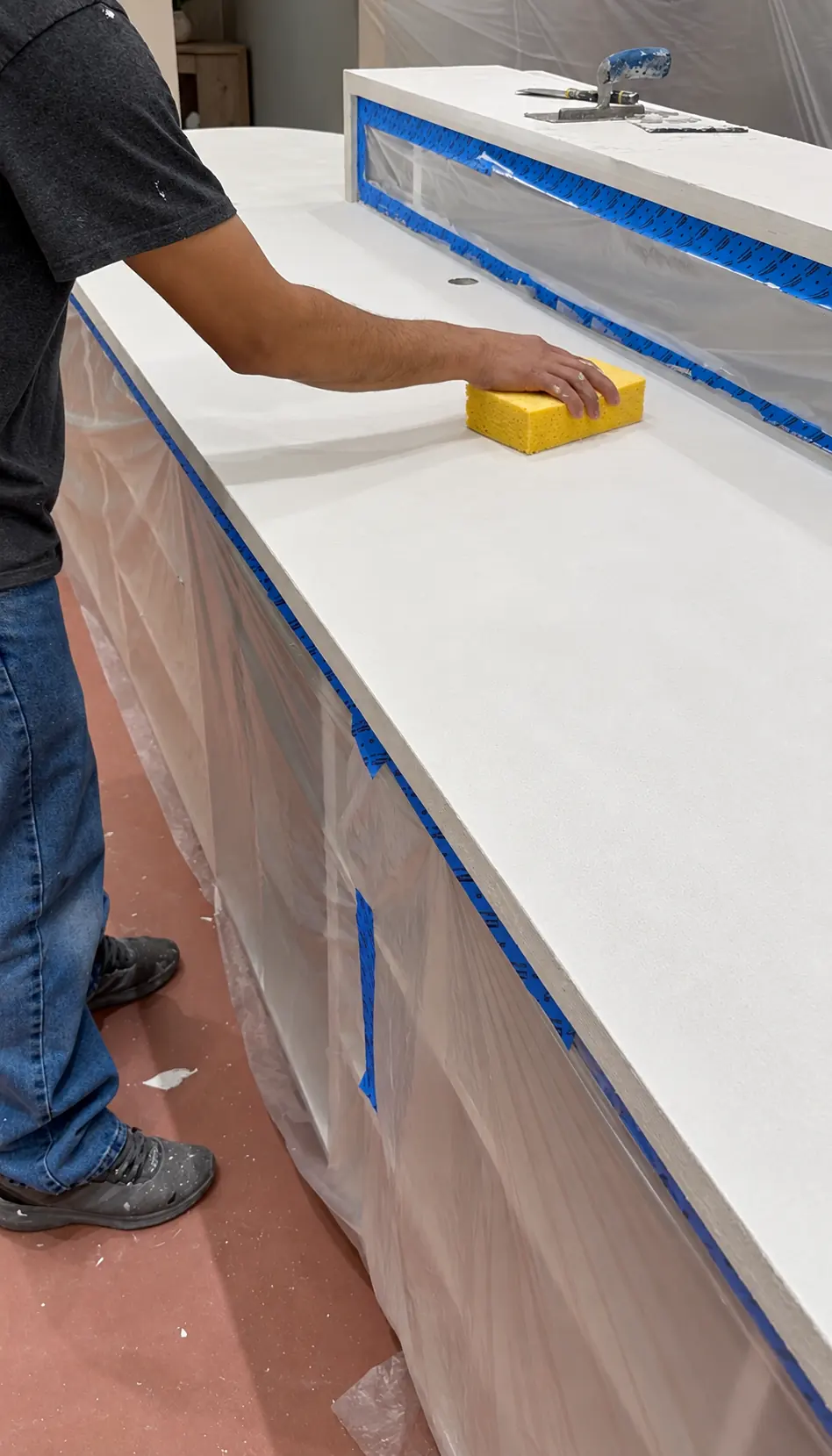 Sponging and refining the finished microcement surface on the Veiled retail checkout counter in Clifton, NJ before sealing