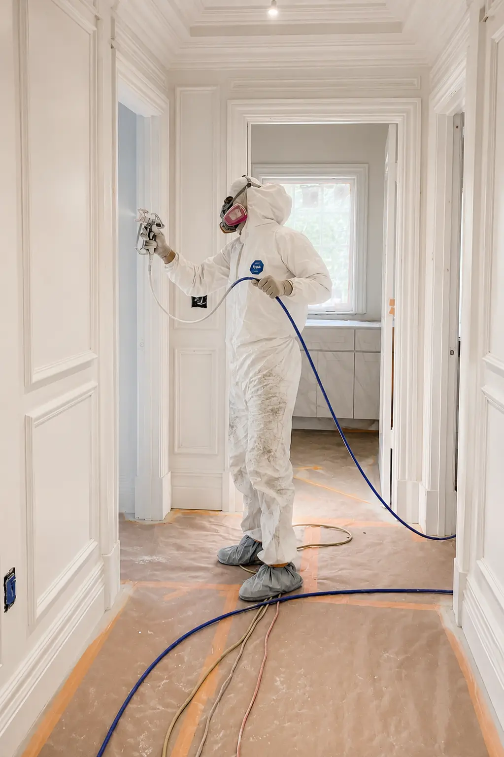 Painter spray-finishing paneled millwork in a Wayne, NJ hallway