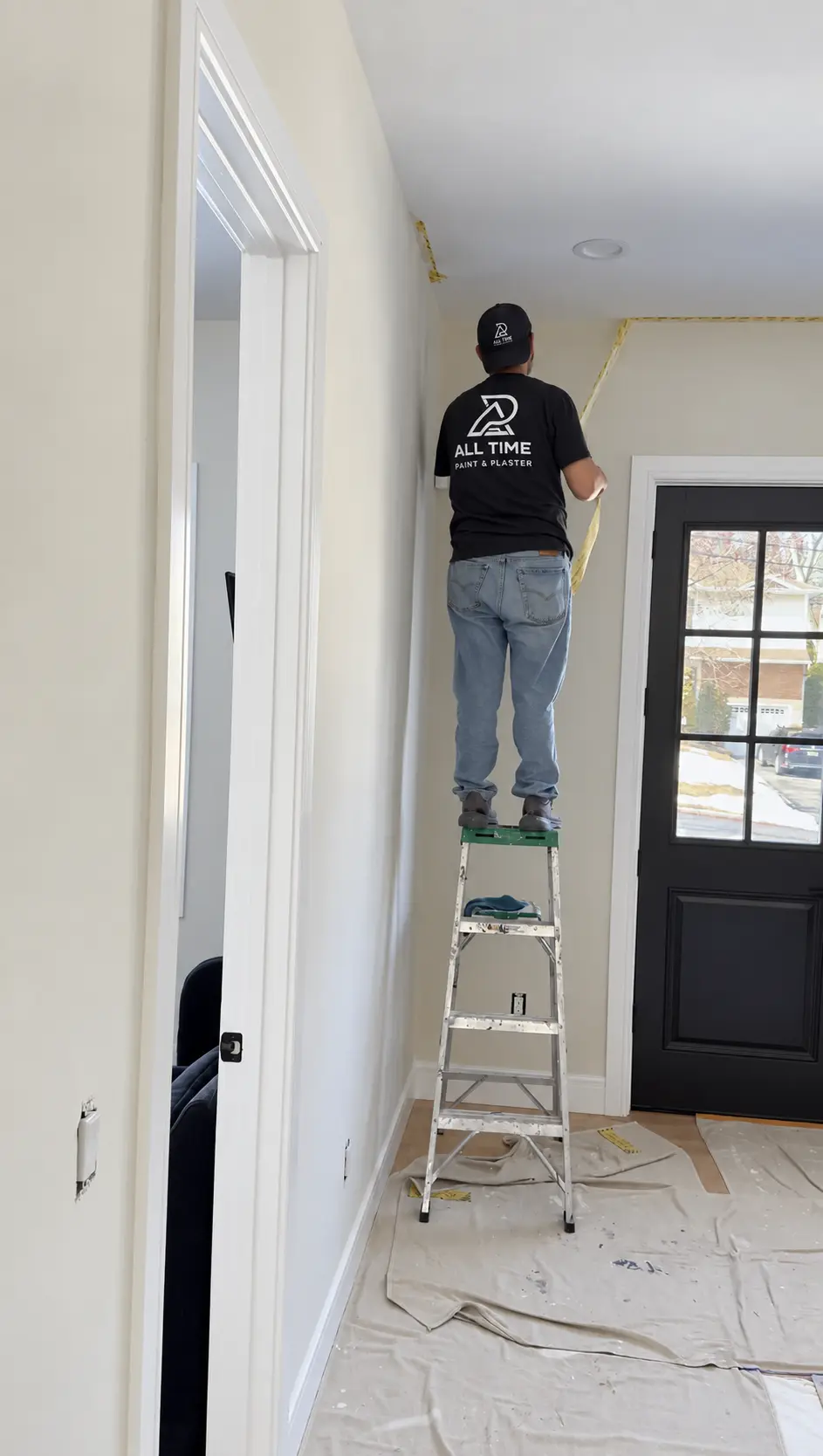Painter preparing and masking an interior entryway wall before the limewash finish is applied.