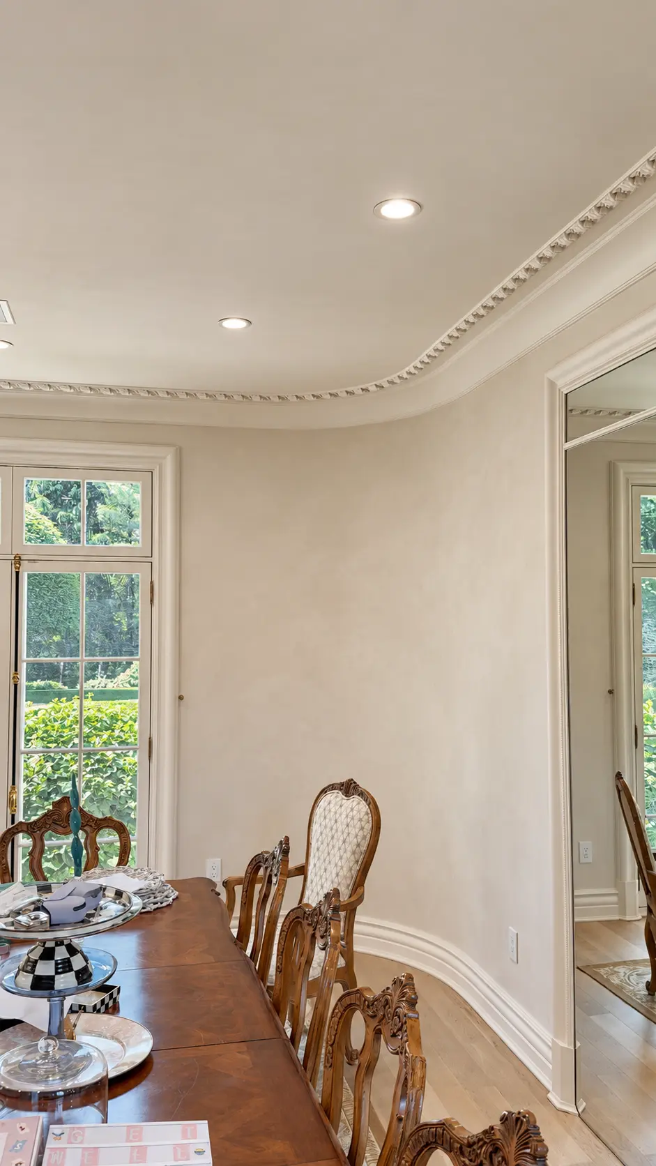 Curved dining room walls finished in soft ivory limewash beneath ornate crown molding in Franklin Lakes, NJ