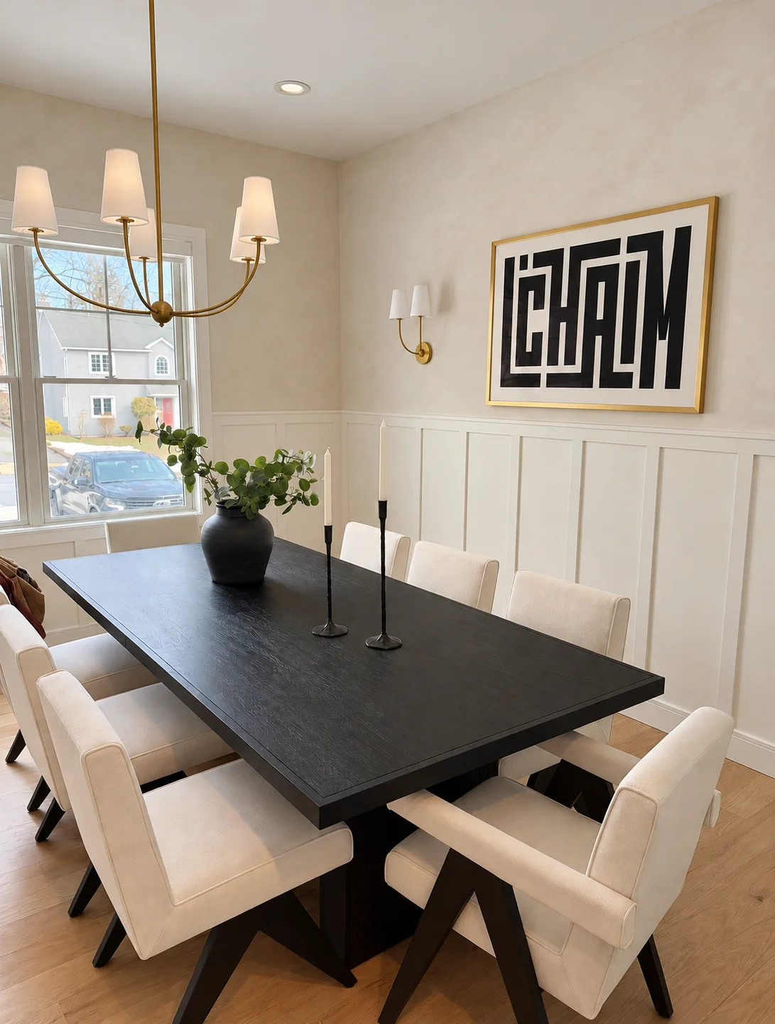 Full view of a warm white limewash dining room with black dining table, cream chairs and brass fixtures in Glen Rock NJ