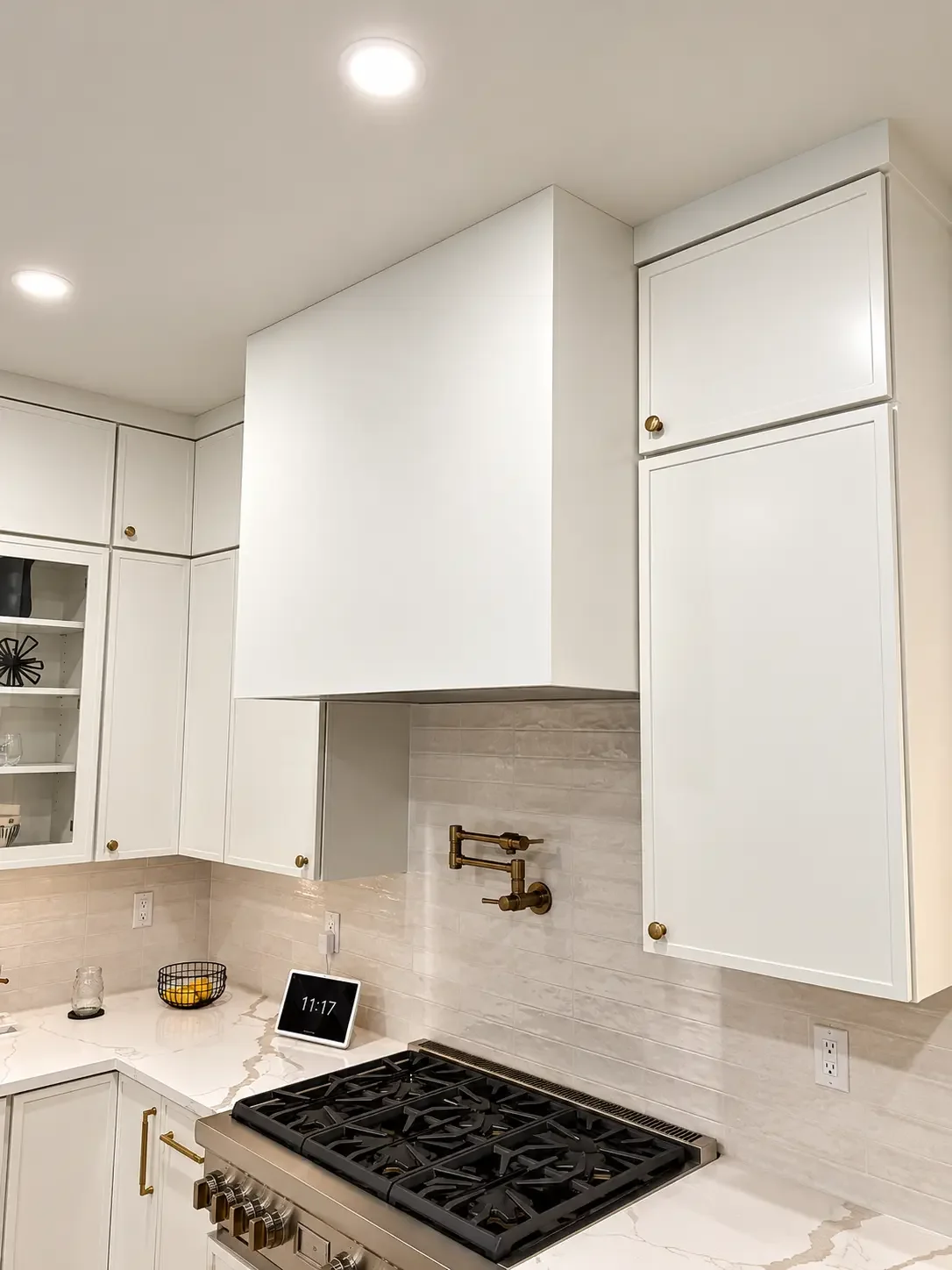 Plain white range hood above the gas range and tile backsplash before decorative plaster — Ridgewood, NJ